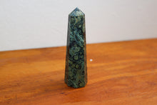 Load image into Gallery viewer, Swirly patterned Kambaba Jasper Tower with deeo Forest greens and light sage green inclusions, sitting atop an orange bench
