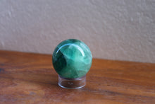 Load image into Gallery viewer, Light coloured small sized polished Fluorite sphere with various shades of Green and aqua inclusions, on stand (not included)