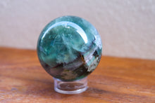 Load image into Gallery viewer, Light coloured small sized polished Fluorite sphere with Purple, Green and aqua inclusions, on stand (not included)