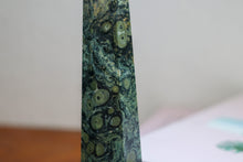 Load image into Gallery viewer, Close up of Swirly patterned Kambaba Jasper Tower with deeo Forest greens and light sage green inclusions, sitting atop a book
