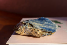 Load image into Gallery viewer, Singular Sea Blue Kyanite Cluster, Hand sized with yellow and brown inclusions, sitting on top of two books