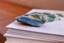 Load image into Gallery viewer, Singular Sky Blue Kyanite Cluster, Hand sized with yellow and brown inclusions, sitting on top of two books
