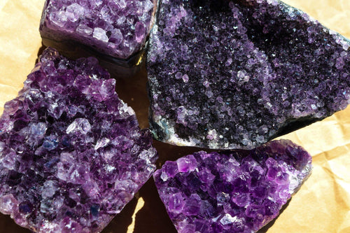 Group Photo of 4 Amethyst Clusters ranging in size, they are a deep shade of purple, photo is taken birdseye