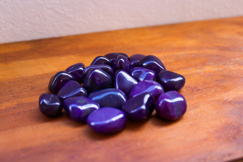 A pile of Purple Agate tumbles varying in medium to dark tones of Purple
