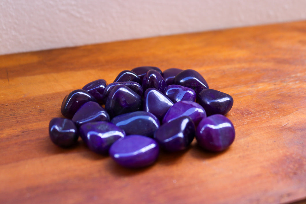 A pile of Purple Agate tumbles varying in medium to dark tones of Purple