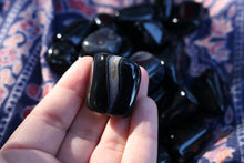 Load image into Gallery viewer, A close up of a Shiny Black Agate tumble with an orca like inclusions
