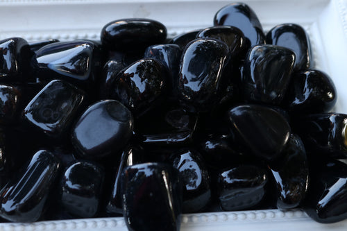 A large pile of Shiny Black Agate tumbles with orca like inclusions