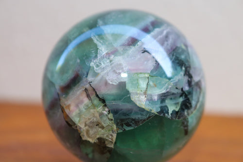 Close up of light coloured medium sized polished Fluorite sphere with Purple, Pink, Green and aqua inclusions