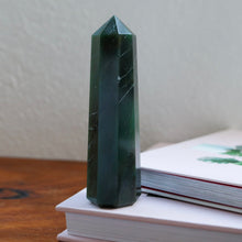 Load image into Gallery viewer, Deep Emerald Green Aventurine Tower (point) sitting atop a book
