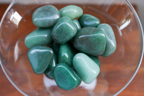 Handful of Green Aventurine Tumbles variying in shades of Green, placed in a clear martini glass