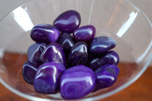 Load image into Gallery viewer, Handful of Purple Agate tumbles varying in medium to dark tones of Purple, held in a clear martini glass
