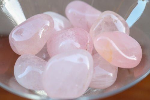 Close up - A handful of Blush Light Pink Rose Quartz Tumbles, held in a clear martini glass