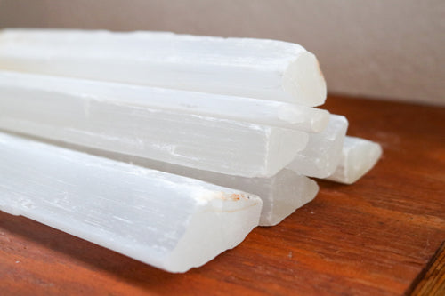 Long Selenite bars (wands) stacked on top of each other to show size, white colour with some yellow inclusions