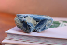 Load image into Gallery viewer, Singular Ocean and light Blue Kyanite Cluster, Hand sized with yellow and clear inclusions, sitting on top of two books
